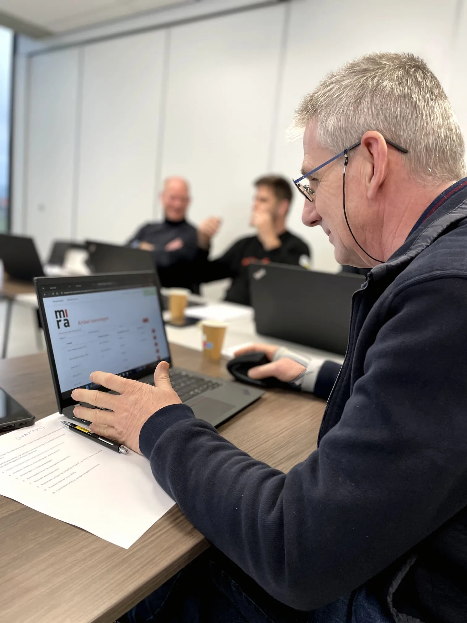 Deelnemers volgen een MIRA Software-opleiding met laptops