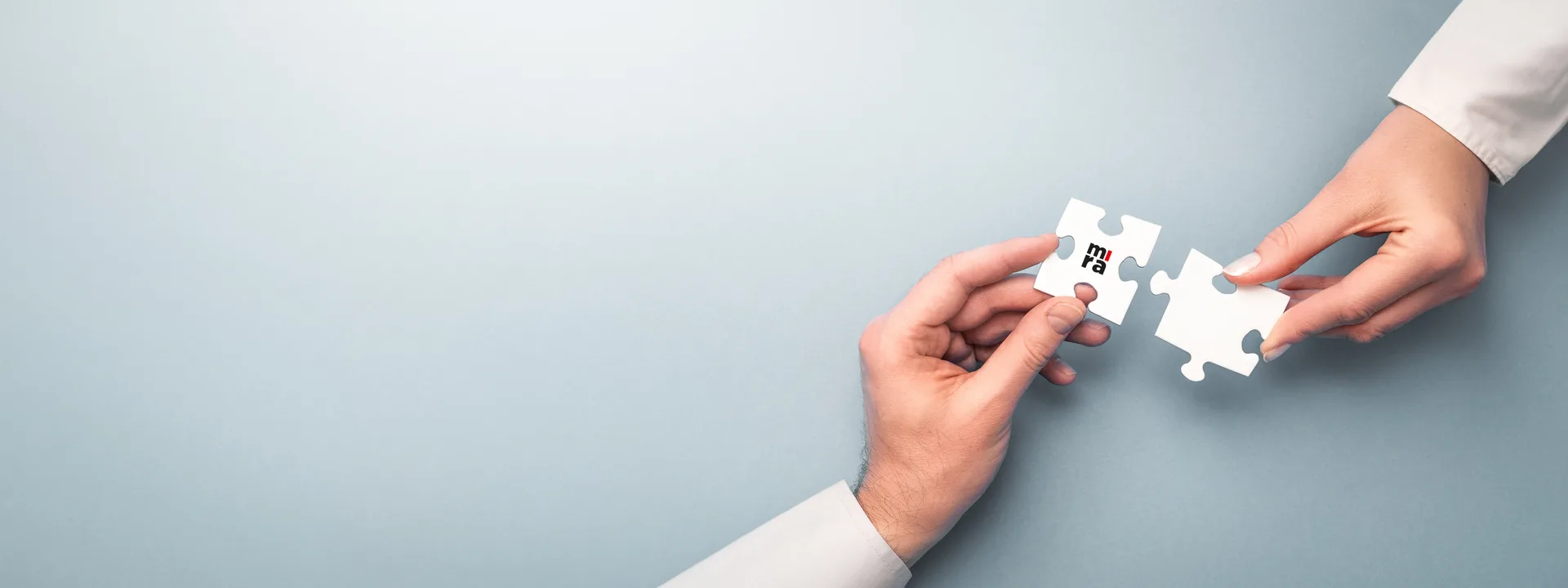 Twee handen verbinden puzzelstukken met het MIRA-logo